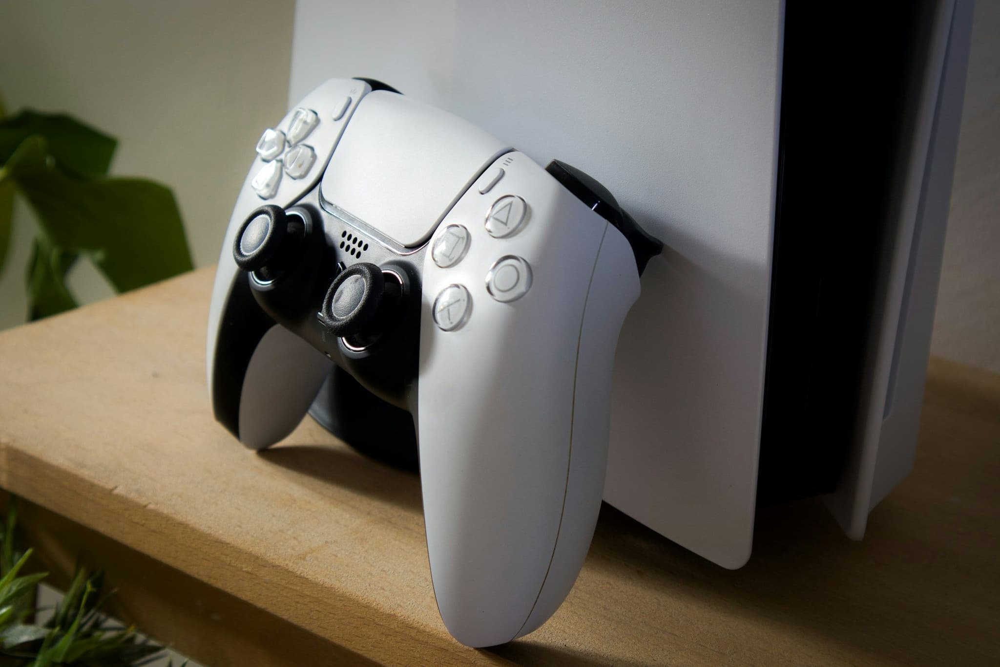 White PlayStation 5 and controller on a wooden shelf